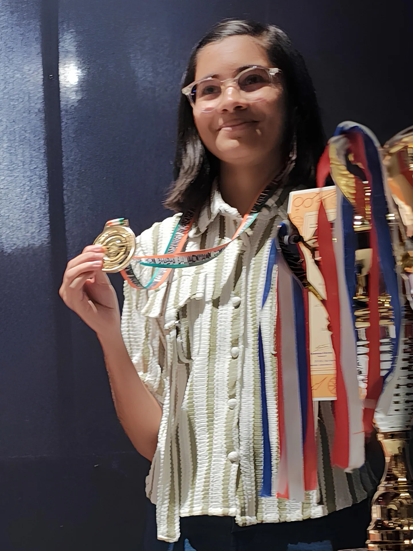 A smiling student proudly holding up her medals