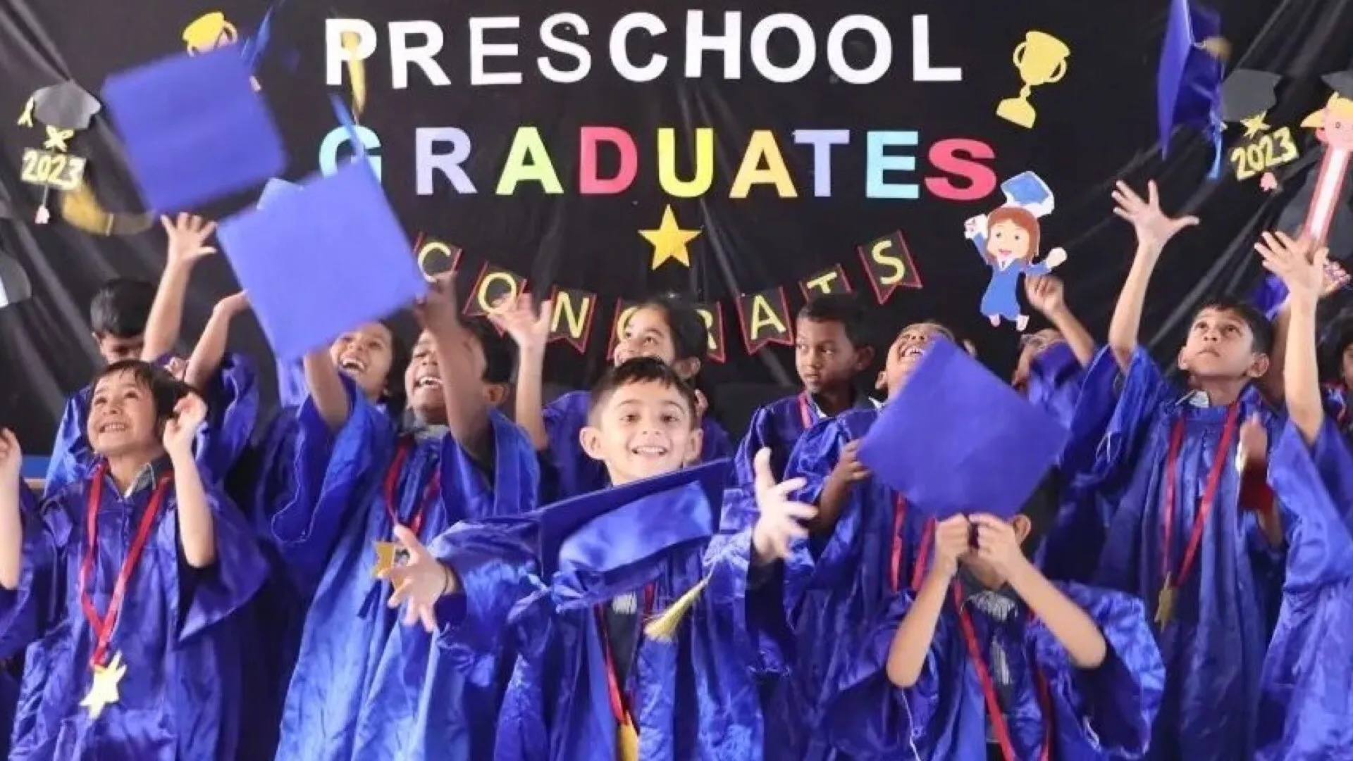 Pre-primary graduates celebrating in caps and gowns