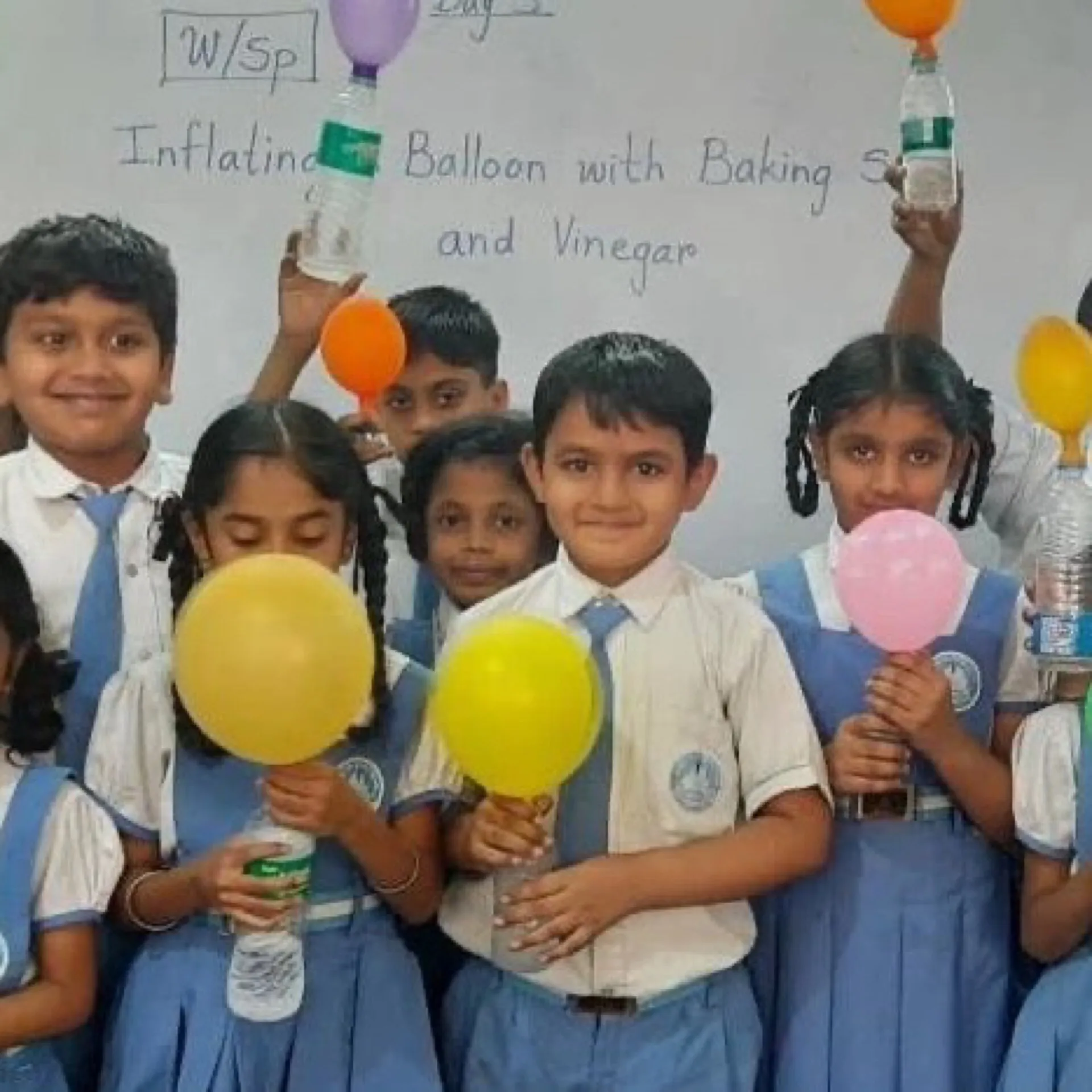 Primary students holding up balloons inflated during a baking-soda and vinegar experiment