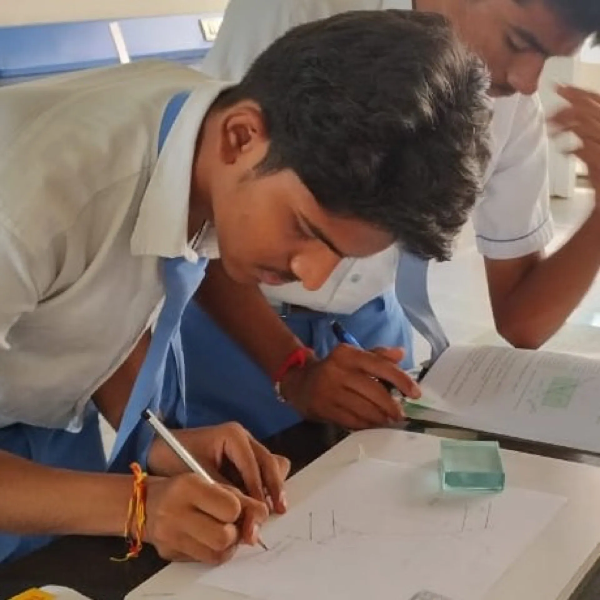 A secondary student concentrating while writing in a notebook
