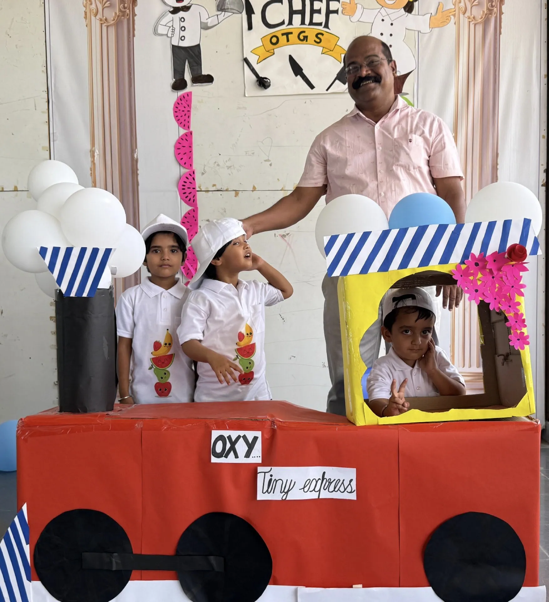 Young campers in chef caps posing with a cardboard train at the summer camp