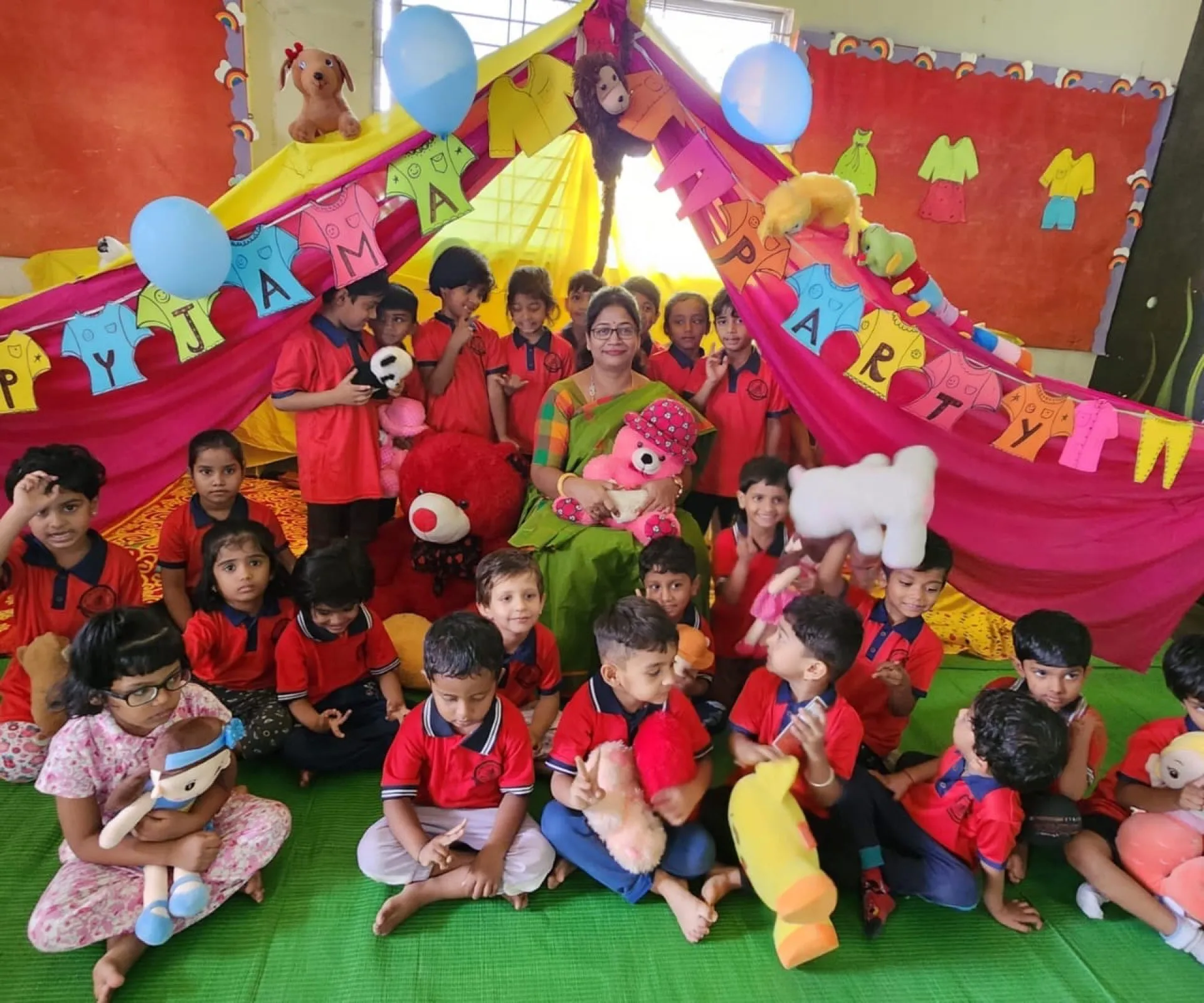 Children with their teacher and soft toys at a pyjama party